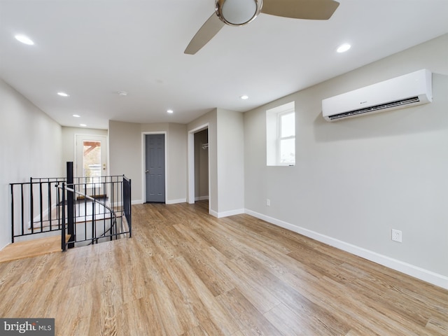 spare room featuring light hardwood / wood-style flooring, a wall unit AC, and ceiling fan