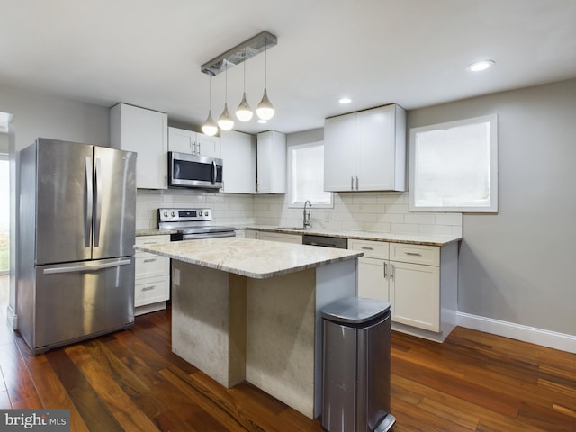 kitchen with white cabinetry, decorative light fixtures, dark hardwood / wood-style floors, a kitchen island, and stainless steel appliances