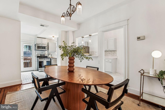 dining space with a chandelier and light wood-type flooring