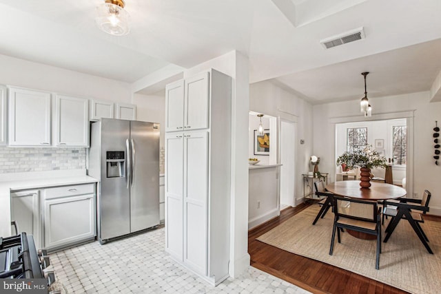 kitchen featuring pendant lighting, tasteful backsplash, stainless steel appliances, and light hardwood / wood-style flooring