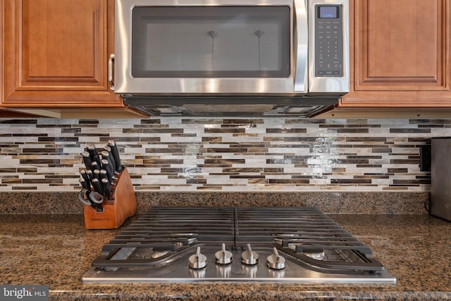 interior details with dark stone counters, appliances with stainless steel finishes, and decorative backsplash