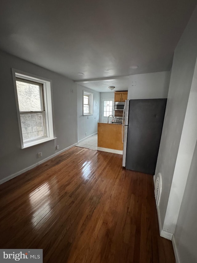 unfurnished living room with a healthy amount of sunlight, sink, and dark hardwood / wood-style flooring