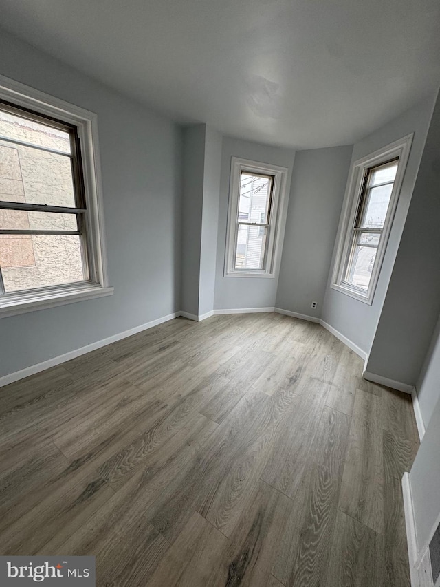 unfurnished room with a healthy amount of sunlight and hardwood / wood-style floors