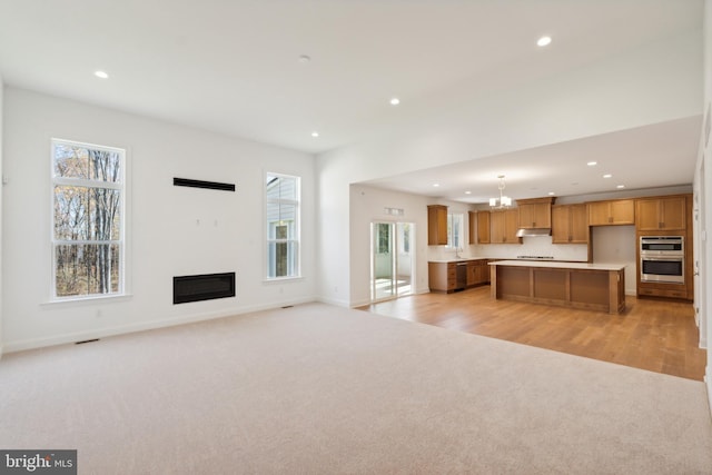 unfurnished living room featuring a notable chandelier and light colored carpet