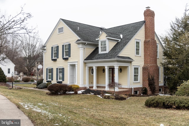 view of front of house with a shingled roof, a chimney, and a front yard