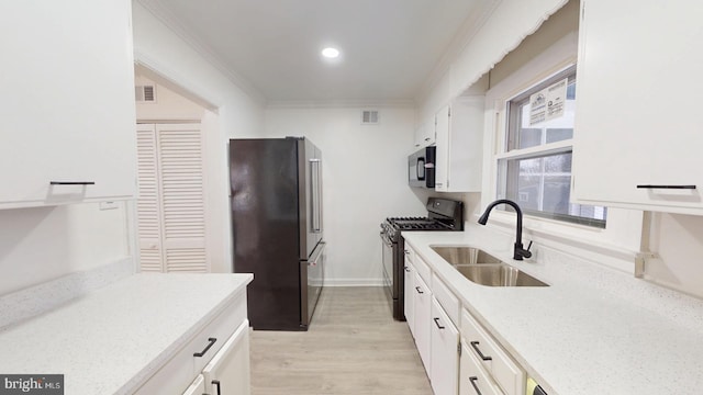 kitchen with high quality fridge, a sink, white cabinetry, ornamental molding, and gas range oven