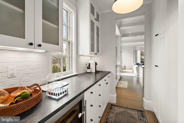 kitchen with decorative backsplash, white cabinets, dark countertops, glass insert cabinets, and dark wood-type flooring