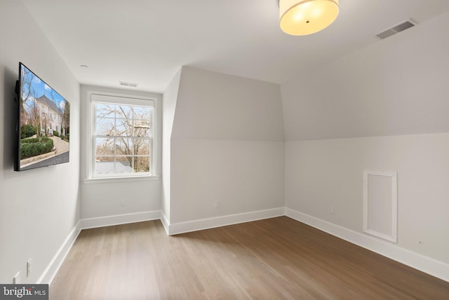 additional living space with wood finished floors, visible vents, and baseboards