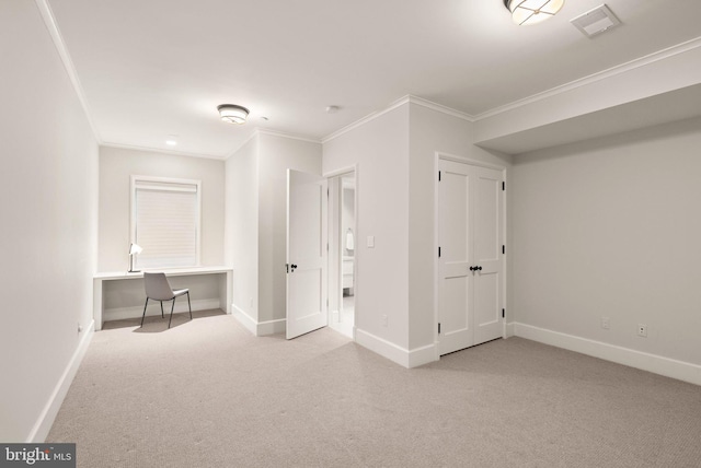 below grade area featuring visible vents, baseboards, ornamental molding, carpet flooring, and built in desk