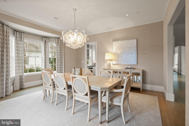 dining area featuring crown molding, light wood-style flooring, baseboards, and an inviting chandelier