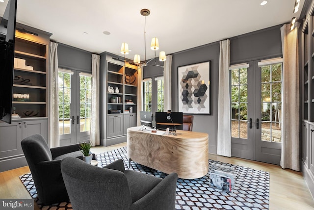 office featuring light wood-type flooring, french doors, and a notable chandelier