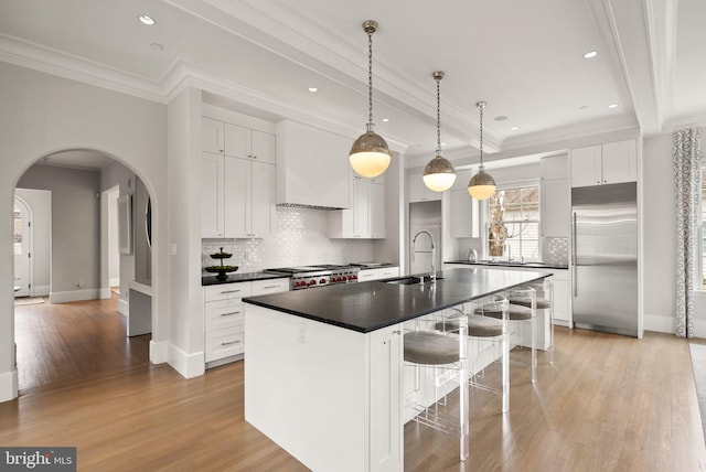 kitchen featuring built in refrigerator, dark countertops, beam ceiling, and a sink