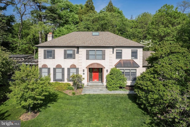 view of front of home featuring roof with shingles, a front yard, and a chimney
