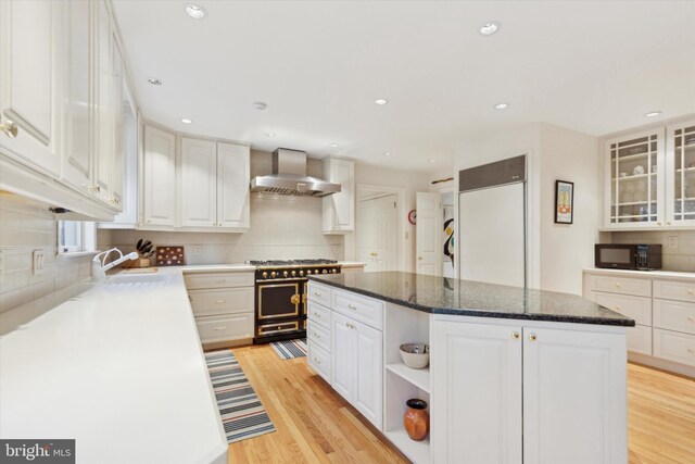 kitchen featuring decorative backsplash, a kitchen island, black microwave, wall chimney range hood, and double oven range