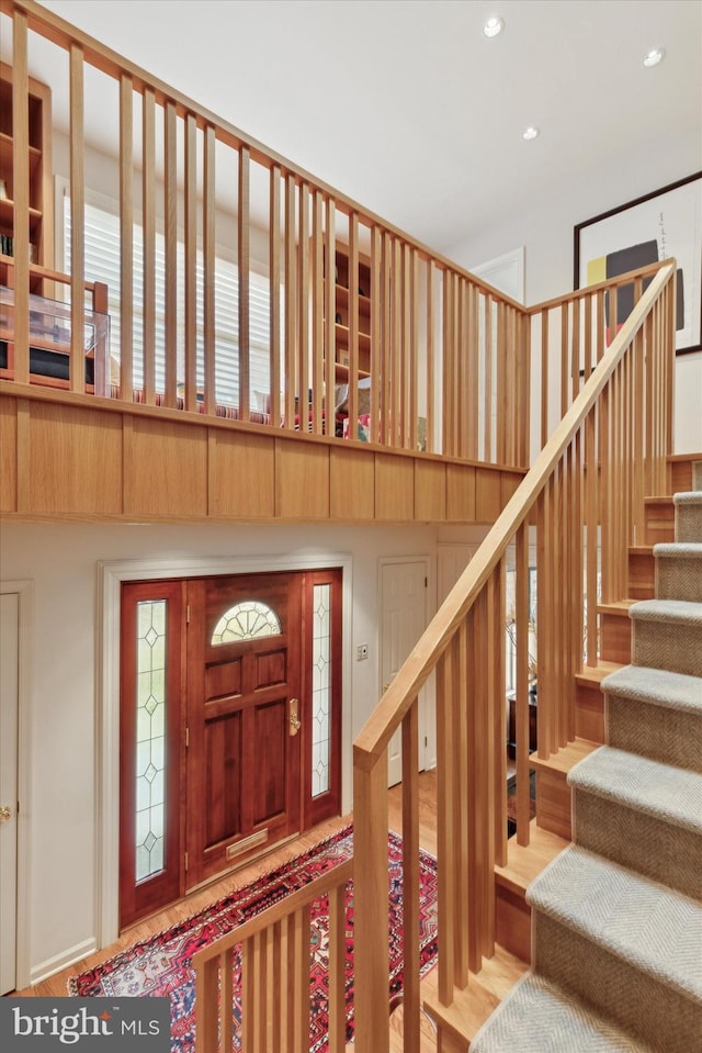 entryway featuring recessed lighting, a high ceiling, stairs, and wood finished floors