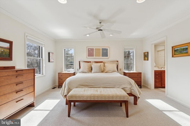 bedroom featuring light carpet, a ceiling fan, baseboards, ensuite bathroom, and ornamental molding