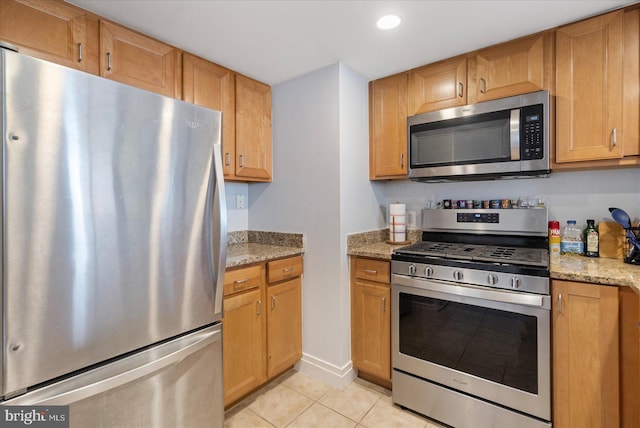 kitchen with light stone counters, recessed lighting, appliances with stainless steel finishes, light tile patterned flooring, and baseboards