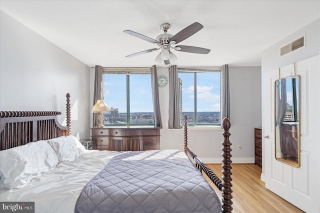 bedroom featuring a ceiling fan, light wood-type flooring, visible vents, and baseboards