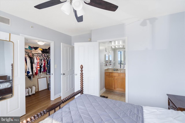 bedroom featuring a walk in closet, a closet, visible vents, connected bathroom, and a sink