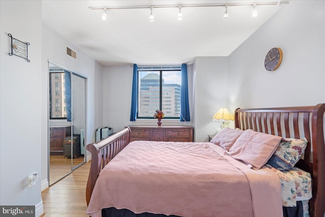 bedroom with light wood-type flooring, visible vents, and a closet