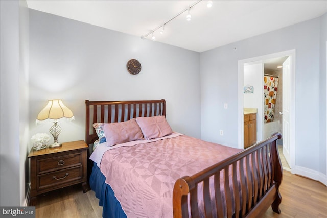 bedroom featuring light wood-style flooring, baseboards, and connected bathroom