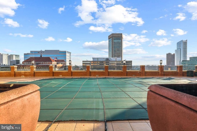 view of pool featuring a view of city and fence