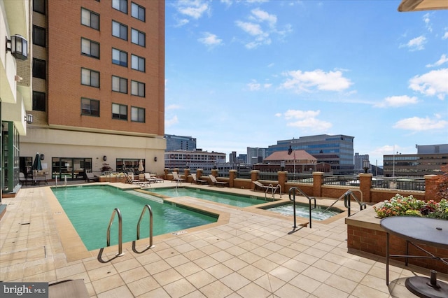 community pool with a patio area, a community hot tub, and a city view