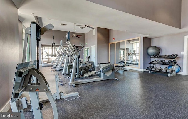 gym featuring a ceiling fan, a high ceiling, visible vents, and baseboards