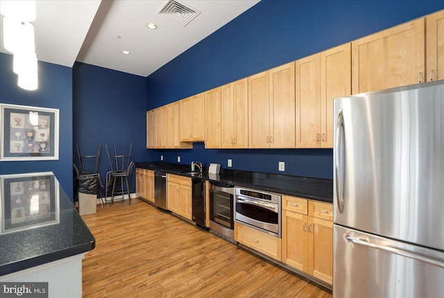 kitchen with wine cooler, stainless steel appliances, a sink, light brown cabinetry, and dark countertops