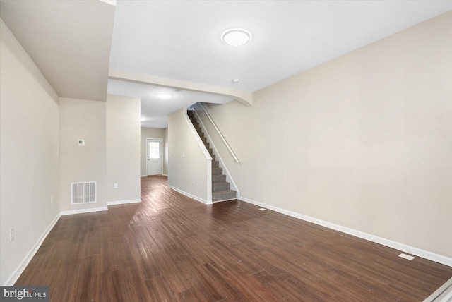 unfurnished living room featuring dark wood-type flooring, stairway, visible vents, and baseboards