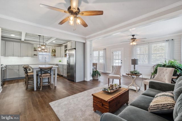 living room with beam ceiling, crown molding, dark wood-type flooring, ceiling fan, and coffered ceiling