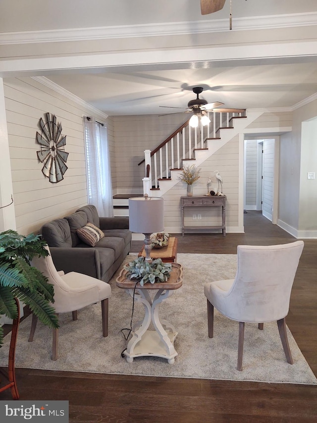 living room with baseboards, a ceiling fan, ornamental molding, wood finished floors, and beam ceiling