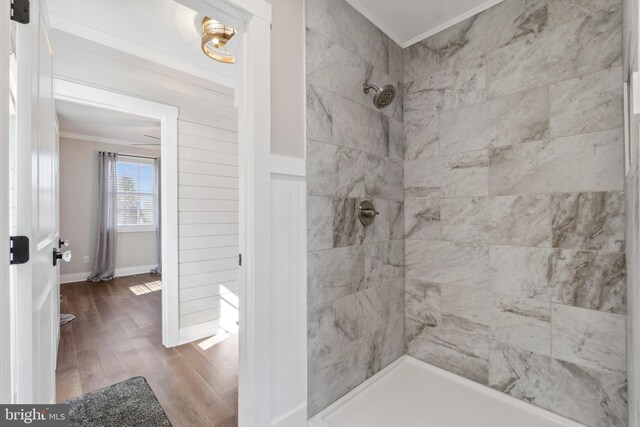 bathroom with ornamental molding, tiled shower, and wood finished floors