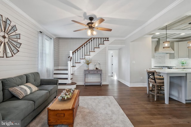 living room with dark wood-type flooring, a ceiling fan, baseboards, stairs, and ornamental molding