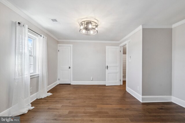 spare room with crown molding, visible vents, wood finished floors, a chandelier, and baseboards