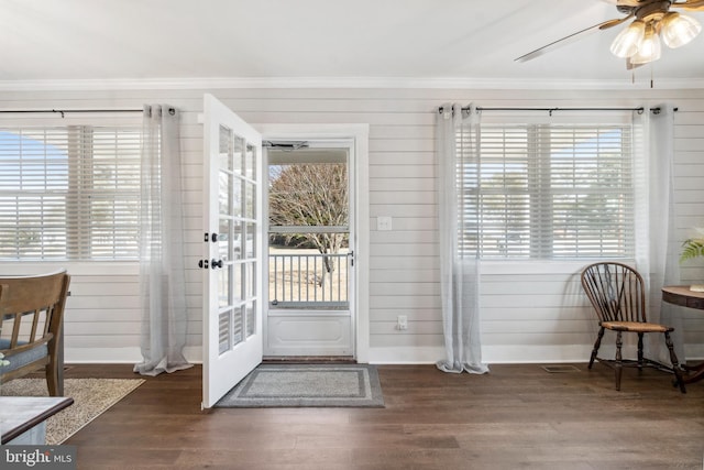 doorway with baseboards, wood finished floors, and crown molding