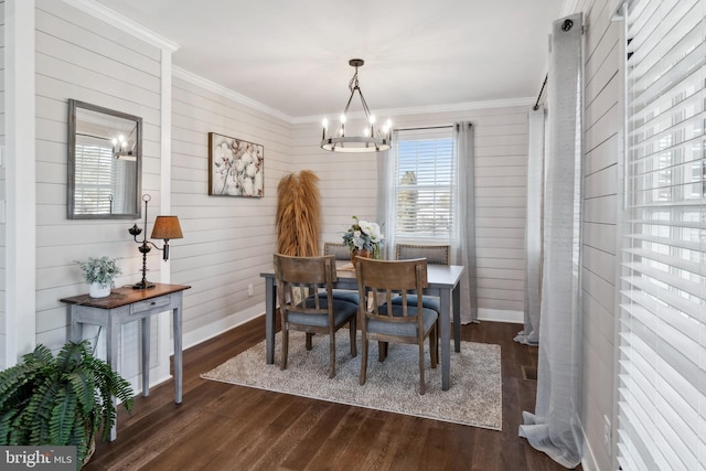 dining space featuring baseboards, ornamental molding, dark wood finished floors, and a notable chandelier