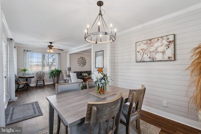 dining space featuring crown molding, dark wood finished floors, baseboards, and ceiling fan with notable chandelier