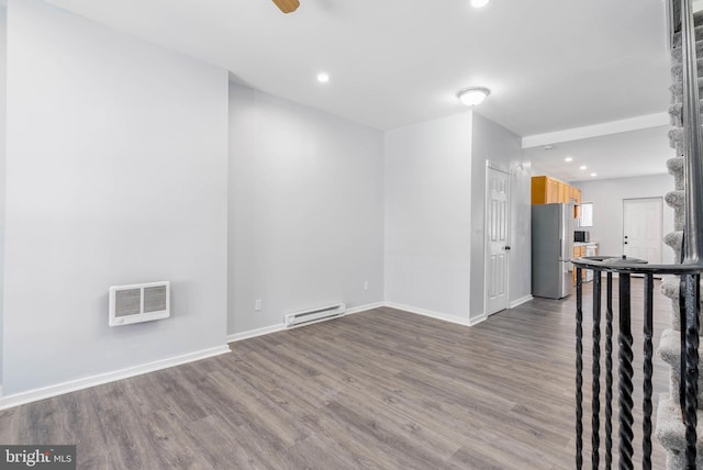 empty room featuring hardwood / wood-style flooring, a baseboard radiator, and ceiling fan