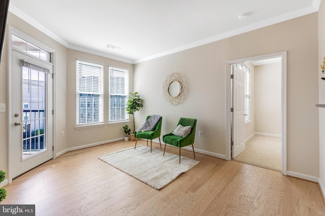 sitting room with crown molding and light hardwood / wood-style flooring