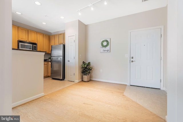 kitchen featuring track lighting, stainless steel appliances, light hardwood / wood-style floors, and light brown cabinets