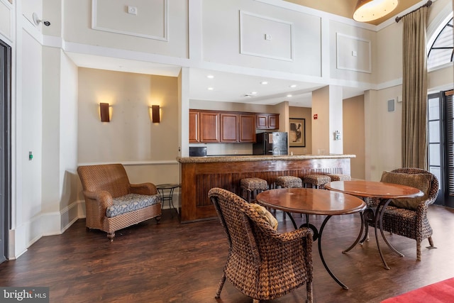 dining area with dark wood-type flooring and a towering ceiling