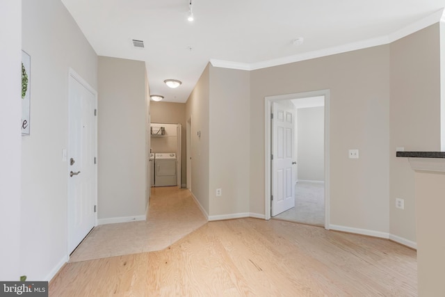 empty room with washer and clothes dryer, ornamental molding, and light wood-type flooring