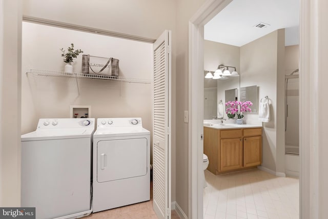 washroom with light tile patterned floors, washing machine and dryer, and sink