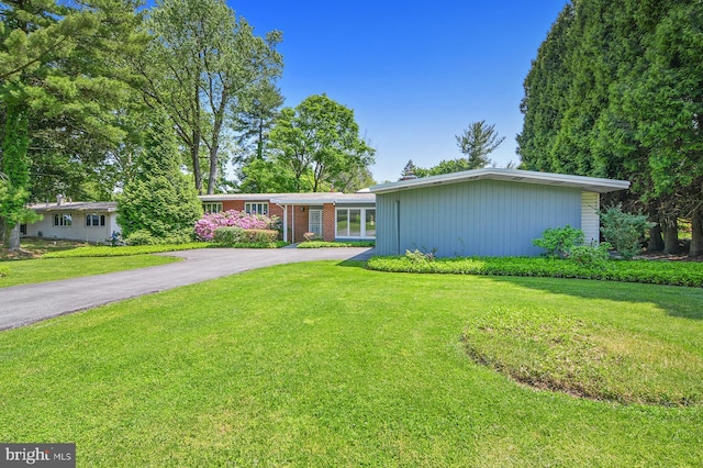 view of front of home featuring a front yard, brick siding, and driveway