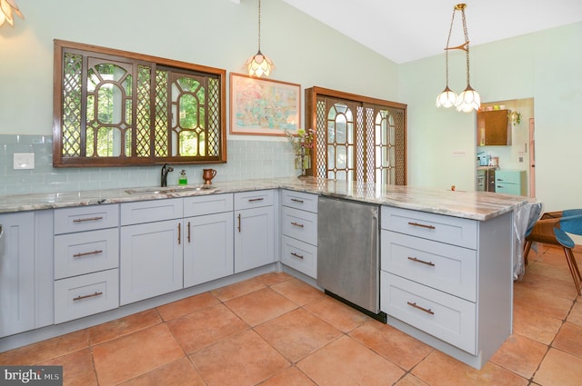 kitchen featuring light stone counters, hanging light fixtures, vaulted ceiling, fridge, and a sink