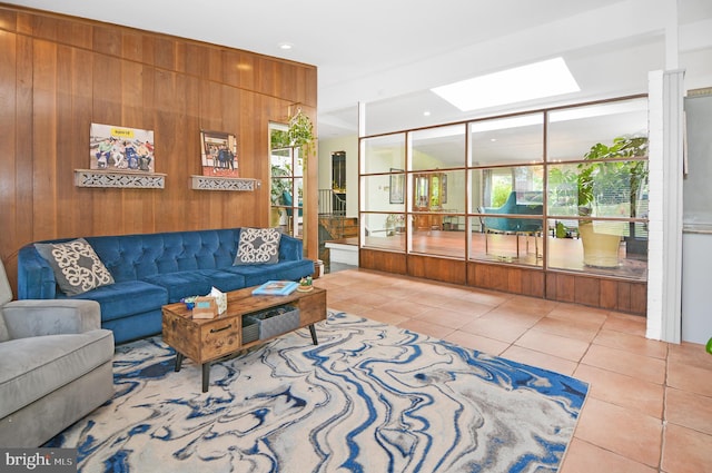 living area with a skylight, light tile patterned floors, and wood walls