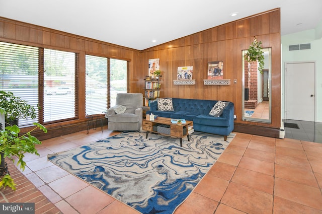 living area featuring lofted ceiling, tile patterned flooring, wooden walls, and visible vents