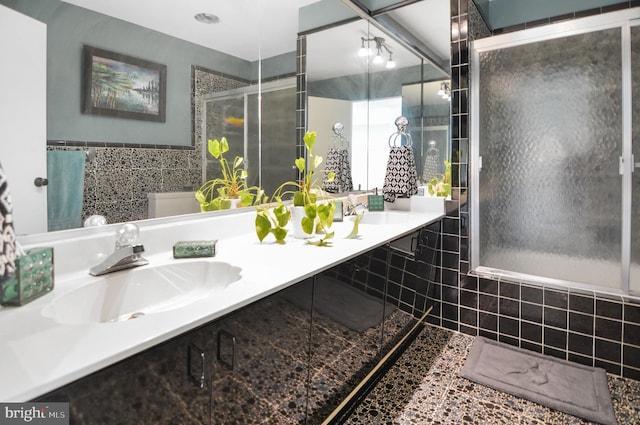 full bath featuring double vanity, a sink, and tile walls