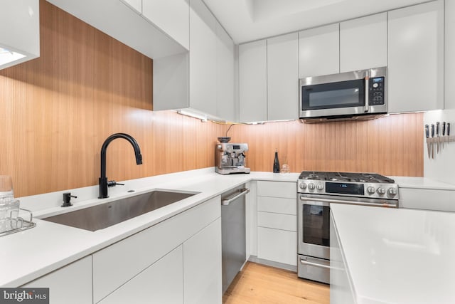 kitchen featuring white cabinetry, stainless steel appliances, light hardwood / wood-style floors, and sink